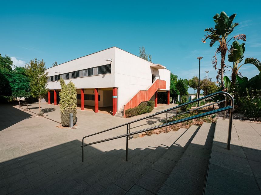 Edificio blanco con escalera exterior roja y palmeras