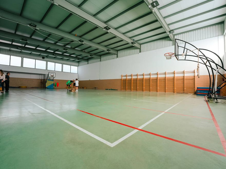 Interior del gimnasio cubierto, con espalderas y canasta