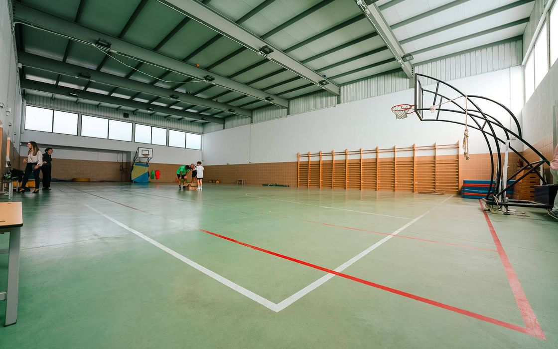 Interior del gimnasio cubierto, con espalderas y canasta
