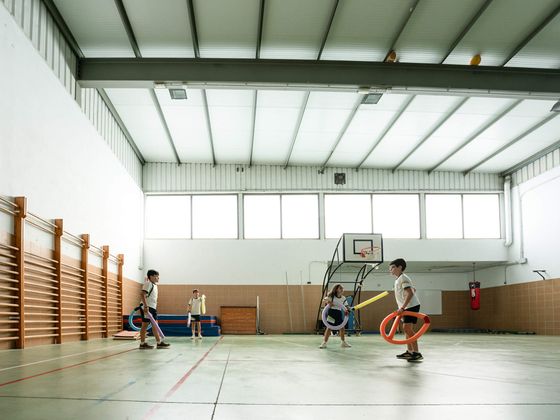Alumnos juegan con aros en el gimnasio
