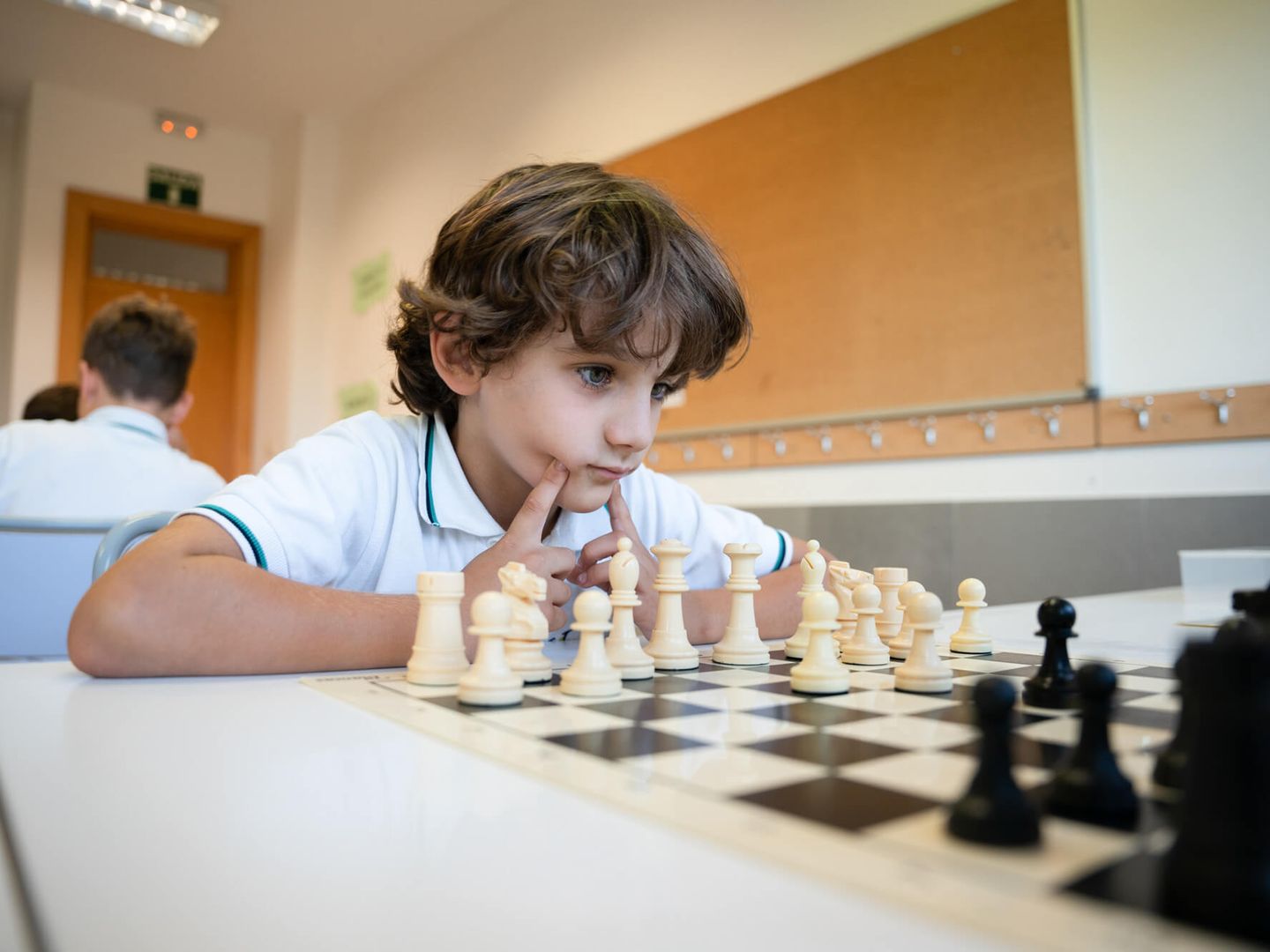Un alumno piensa su jugada ante un tablero de ajedrez