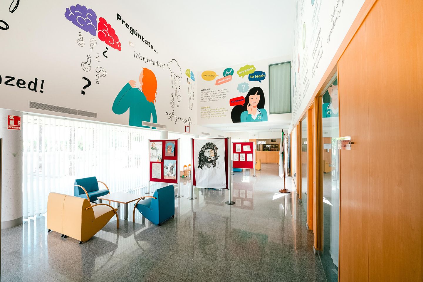 Vestíbulo del colegio con un mural que dice «Pregúntate» y «¡Sorpréndete!»