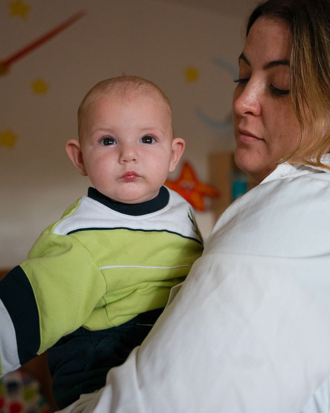 Una educadora sostiene en brazos a un bebé de Nursery School
