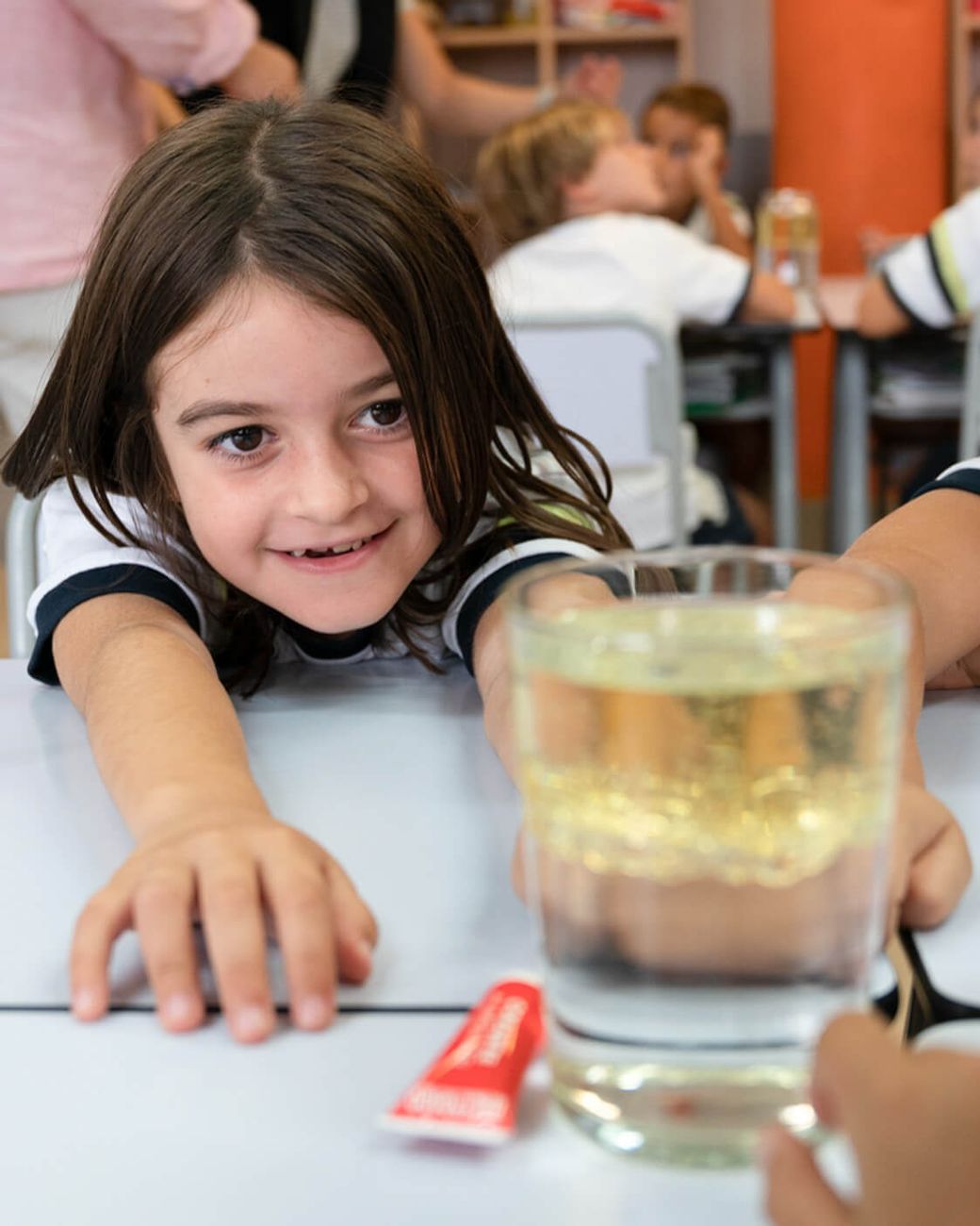 Dos alumnos de Infants observan con asombro un vaso durante un experimento